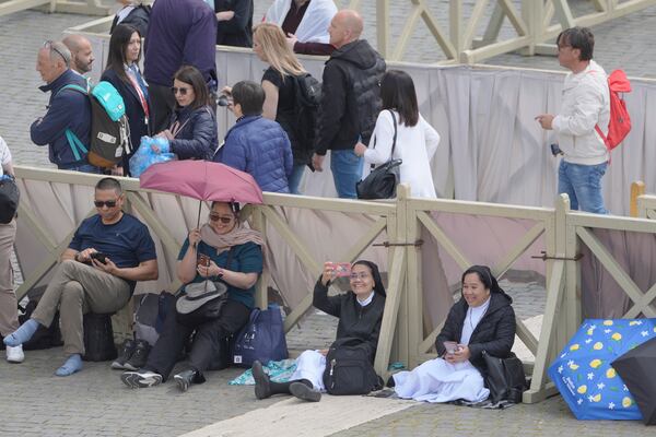 People arrive at St. Peter's Square at the Vatican where 133 cardinals gather on the second day of the conclave to elect successor of late Pope Francis, Thursday, May 8, 2025. (AP Photo/Markus Schreiber)