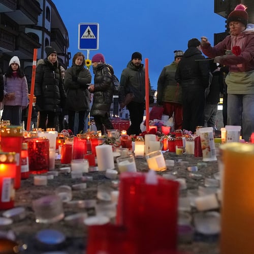 People light candles near the sealed off Le Constellation bar in Crans-Montana, Swiss Alps, Switzerland, Friday, Jan. 2, 2026, where a devastating fire left dead and injured during the New Year's celebrations. (AP Photo/ Antonio Calanni)
