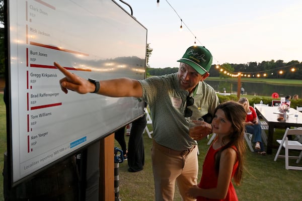 Zach Burden monitors poll results with his daughter, Parker, during an election night party for Georgia gubernatorial candidate Burt Jones at The Rivers Ranch on Tuesday in Jackson. (Hyosub Shin/AJC)