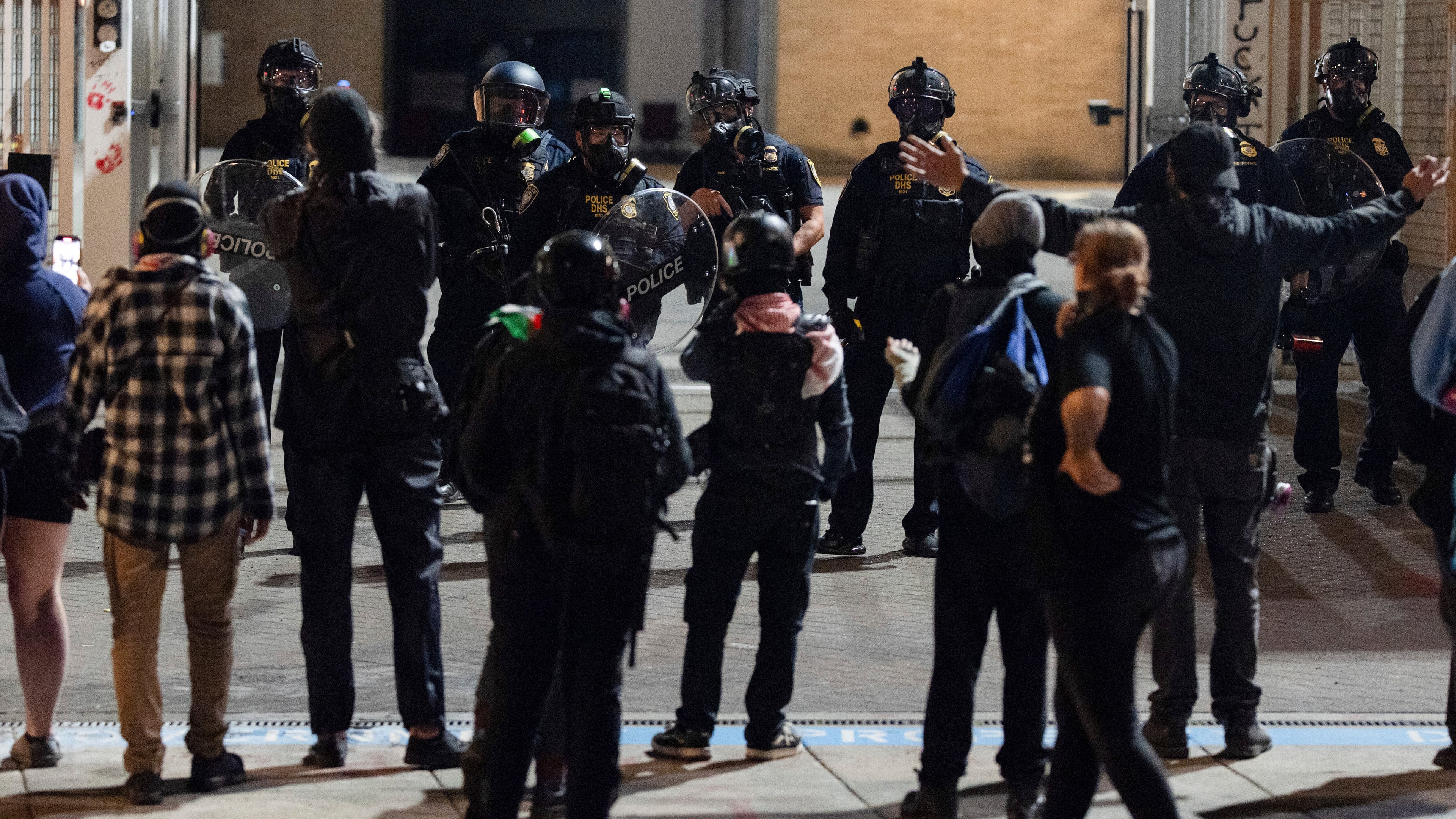 Protesters yell at officers as they walk back to the gates after they created a path for vehicles to exit the U.S. Immigration and Customs Enforcement building in Portland, Ore., on Wednesday, Sept. 10, 2025. (AP Photo/Jenny Kane)