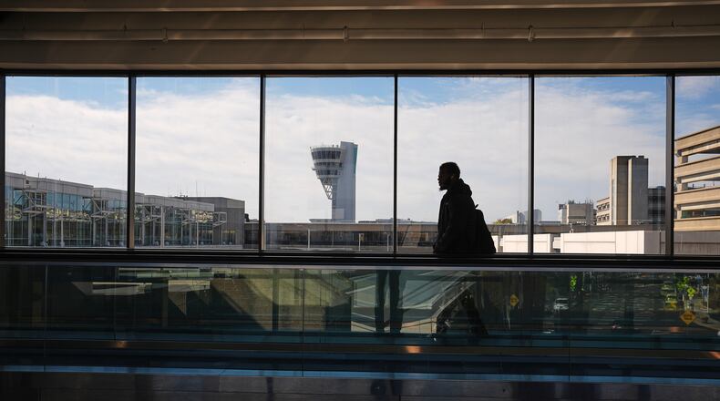 A traveler moves in view of a control tower at Philadelphia International Airport in Philadelphia, Wednesday, Nov. 5, 2025. (AP Photo/Matt Rourke)