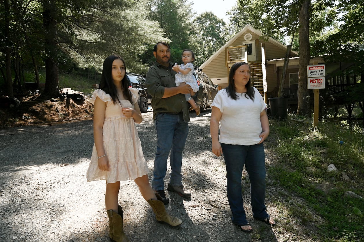 Kristy Guarnieri (right) and husband Courtney Guarnieri stand with their daughters, Stella, 12 (left) and Eliza, 1, on their property in Morganton in North Georgia on Thursday, June 4, 2026. They say their lives have been upturned by animals getting loose from the nearby Hooves and Feathers Petting Farm. (Hyosub Shin/AJC)
