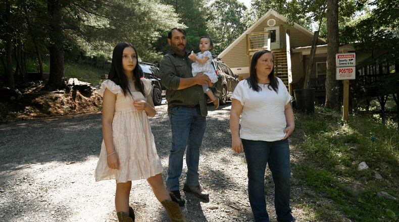 Kristy Guarnieri (right) and husband Courtney Guarnieri stand with their daughters, Stella, 12 (left) and Eliza, 1, on their property in Morganton in North Georgia on Thursday, June 4, 2026. They say their lives have been upturned by animals getting loose from the nearby Hooves and Feathers Petting Farm. (Hyosub Shin/AJC)