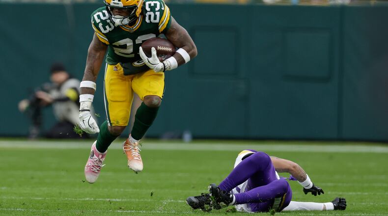 Green Bay Packers running back Emanuel Wilson (23) runs with the football after avoiding a tackle by Minnesota Vikings cornerback Byron Murphy (7), right, during the second half of an NFL football game Sunday, Nov. 23, 2025, in Green Bay, Wis. (AP Photo/Matt Ludtke)