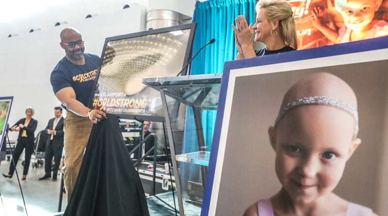 September 20, 2019 Hartsfield-Jackson International Airport: Dr. Kofi Smith, President & CEO, Atlanta Airlines Terminal Company (left) unveils a picture of the gold canopy as Dean Crowe, Founder & CEO, Rally Foundation for Childhood Cancer Research (right) applauds. JOHN SPINK/JSPINK@AJC.COM