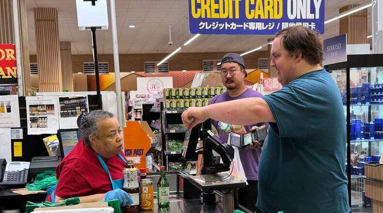 An employee checks a customer's identification card before checking out alcohol at a cash register in a grocery store in Arlington Heights, Ill., Monday, July 6, 2026. (AP Photo/Nam Y. Huh)