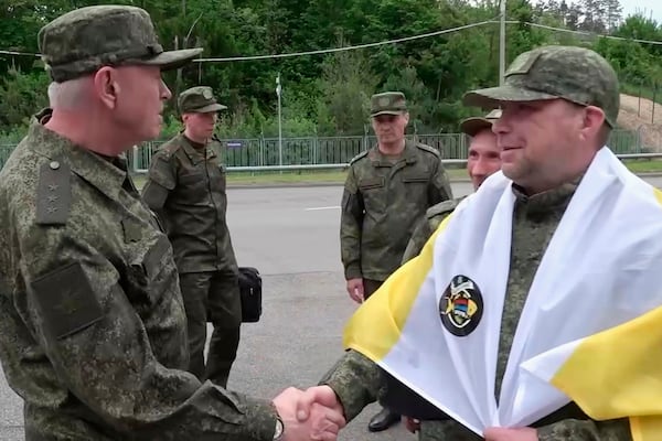 In this photo taken from a video released by Russian Defense Ministry press service, a Russian serviceman, right, speaks on the phone after returning from captivity after an exchange between Russia and Ukraine, at an undisclosed location in Belarus, Saturday, May 24, 2025. (Russian Defense Ministry Press Service via AP)