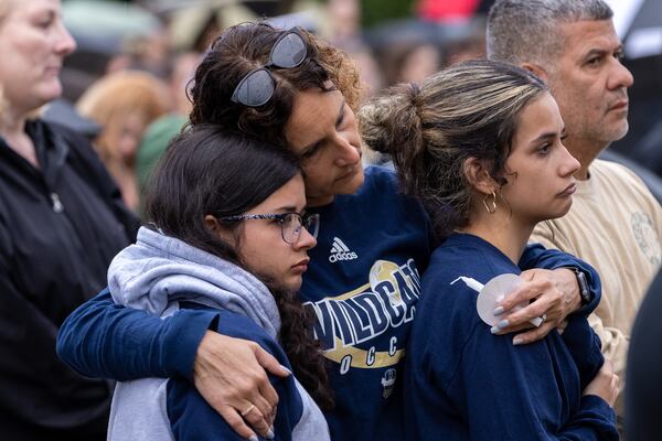 From left, Mya, Darlene and Karina Soto comfort each other at a vigil in Winder days after the 2024 shooting at Apalachee High School. (Arvin Temkar/AJC)
