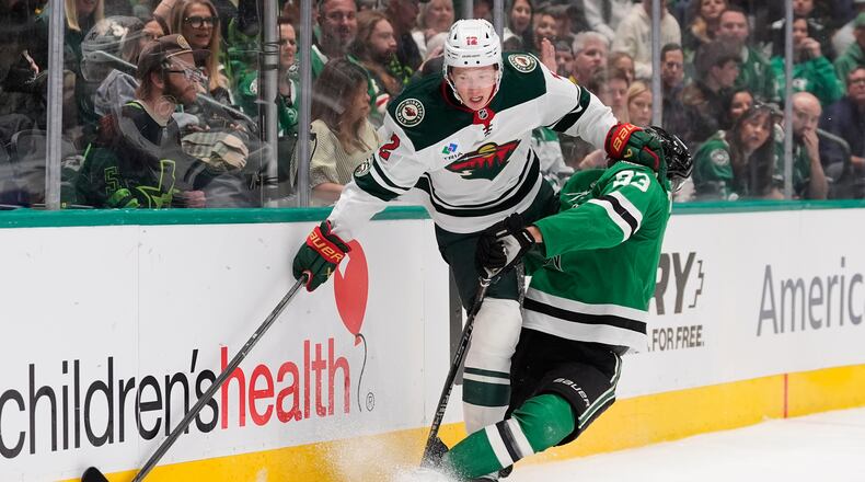 Minnesota Wild left wing Matt Boldy (12) and Dallas Stars center Wyatt Johnston (53) slam into the boards chasing after the puck in the first period of an NHL hockey game Thursday, April 9, 2026, in Arlington, Texas. (AP Photo/Tony Gutierrez)