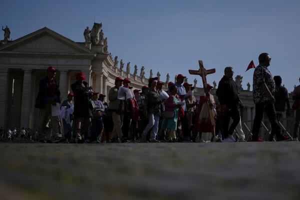 Pilgrims carrying a cross make their way to the Holy Door in St. Peter's Square at the Vatican after Cardinal Camerlengo Kevin Joseph Farrell announced the death of Pope Francis, Monday, April 21, 2025. (AP Photo/Alessandra Tarantino)