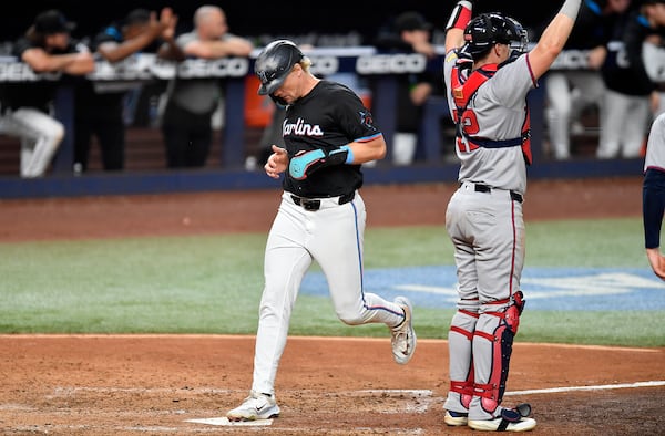 Miami Marlins' Kyle Stowers, left, scores as Atlanta Braves catcher Sean Murphy, right, signals during the sixth inning of a baseball game, Friday, June 20, 2025, in Miami. (AP Photo/Michael Laughlin)