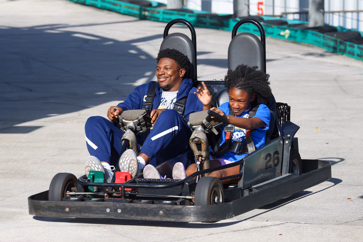 Georgia Tech football player Chuma Okoye rides along with a local child during Pop-Tarts Bowl festivities at Fun Spot America on Tuesday, Dec. 23, 2025, in Orlando, Fla. (Don Montague/Florida Citrus Sports)