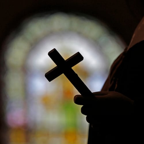 FILE - This Dec. 1, 2012 file photo shows a silhouette of a crucifix and a stained glass window inside a Catholic Church in New Orleans. (AP Photo/Gerald Herbert, File)