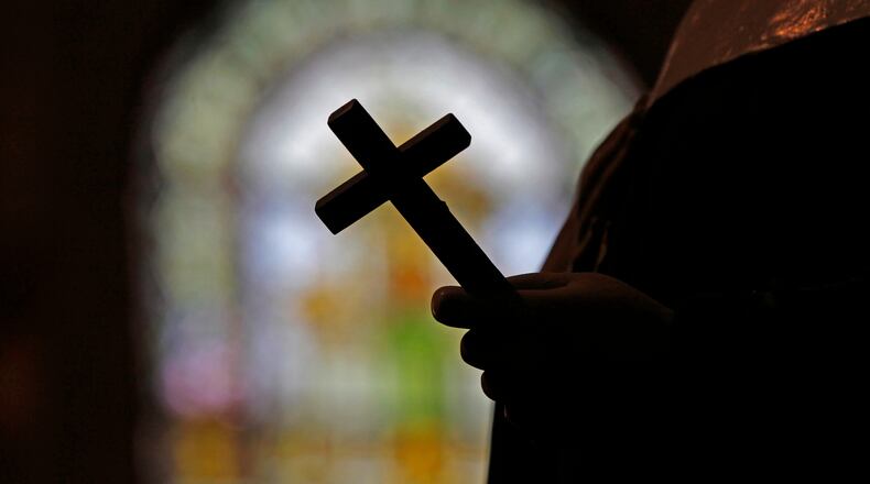 FILE - This Dec. 1, 2012 file photo shows a silhouette of a crucifix and a stained glass window inside a Catholic Church in New Orleans. (AP Photo/Gerald Herbert, File)