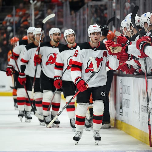 New Jersey Devils center Jack Hughes, center, greets teammates after scoring during the third period of an NHL hockey game against the Anaheim Ducks Sunday, Nov. 2, 2025, in Anaheim, Calif. (AP Photo/William Liang)