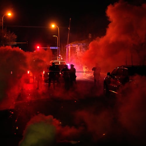 Tear gas surrounds federal law enforcement officers as they leave a scene after a shooting on Wednesday, Jan. 14, 2026, in Minneapolis. (AP Photo/John Locher)