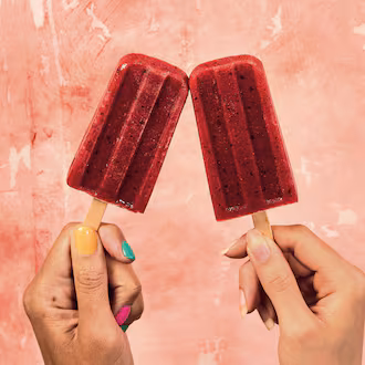 two hands holding one red popsicle each with a pink background