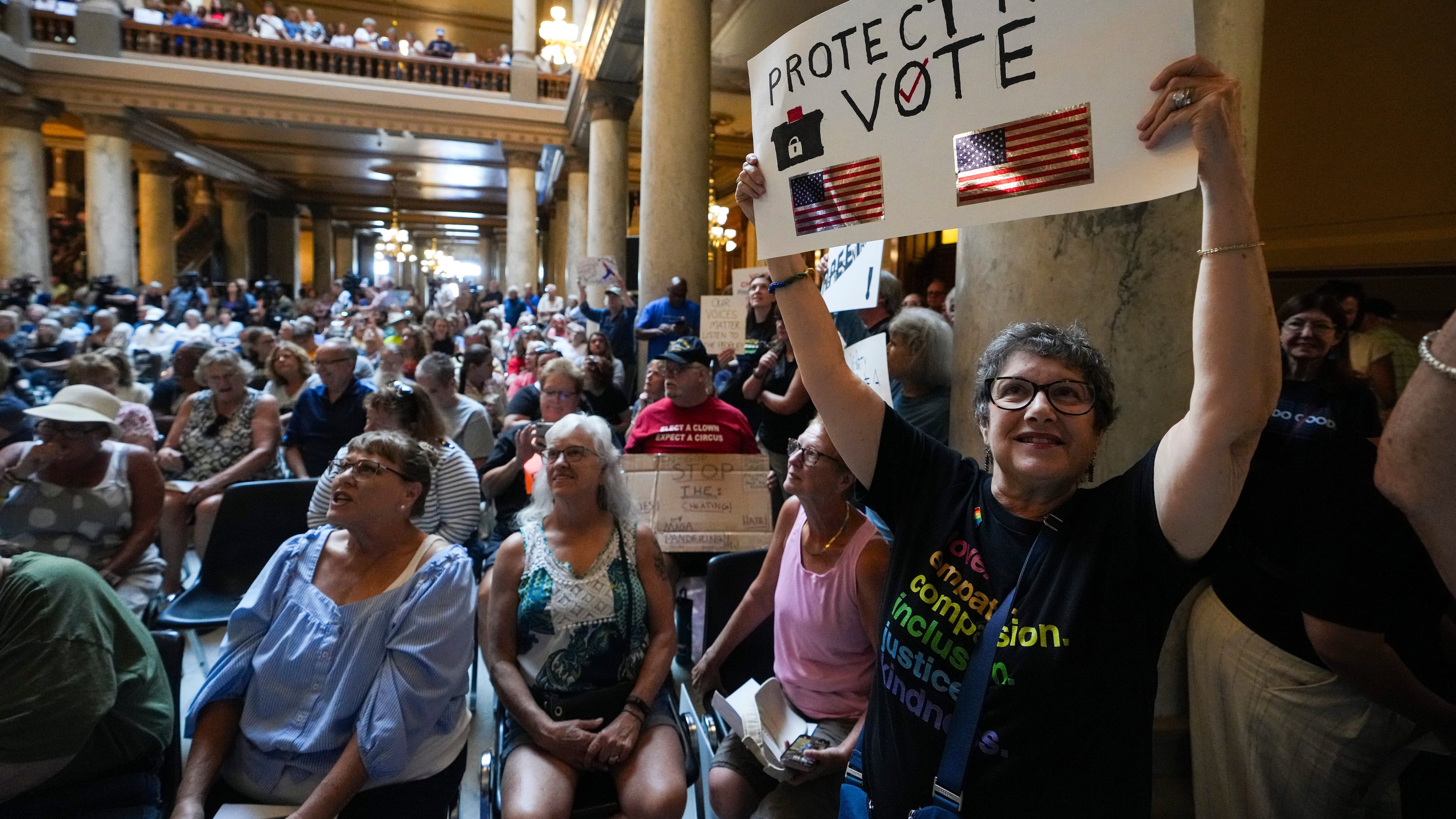 FILE - Annette Groos holds a sign before the start of a rally featuring former Transportation Secretary Pete Buttigieg at the Statehouse in Indianapolis, Thursday, Sept. 18, 2025 for Indiana Democrats amid pressure from President Donald Trump on Republicans who control the state's legislature to redistrict congressional seats. (AP Photo/Michael Conroy, File)