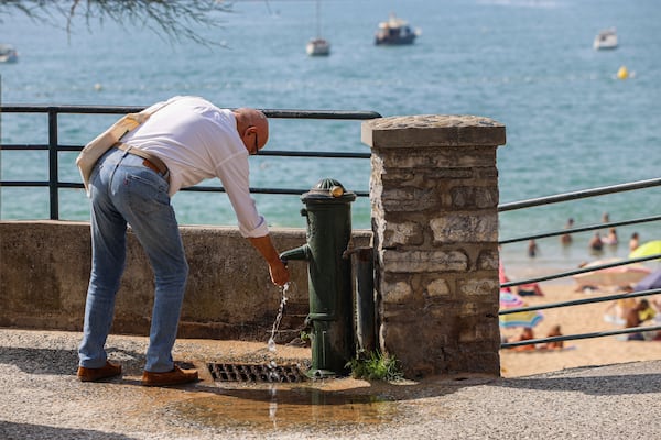 A man refreshes his hands Monday, June 30, 2025 on the seafront in Saint-Jean-de-Luz, southwestern France. (AP Photo/Nicolas Mollo)