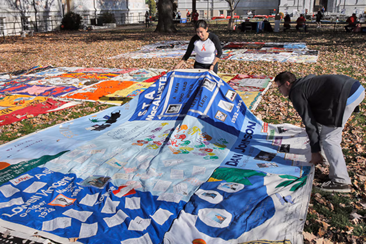 Nina Martinez (left), an AIDS advocate, and Roddy Williams, AIDS Quilt director of operations, straighten a section of the AIDS Quilt last December at Emory University. (Bob Andres/AJC)