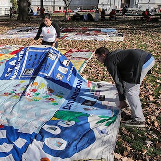 Nina Martinez (left), an AIDS advocate, and Roddy Williams, AIDS Quilt director of operations, straighten a section of the AIDS Quilt last December at Emory University. (Bob Andres/AJC)