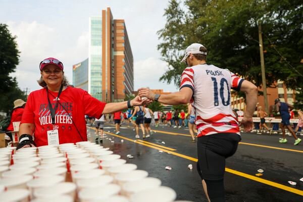 Shoutout to the Peachtree volunteers, whose well-timed water handoffs helped keep thousands of runners moving on race day. (Arvin Temkar/AJC)