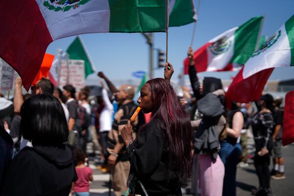 A protester cools down with an icicle while joining other protesters waving Mexican National Flags during a protest to denounce ICE, U.S. Immigration and Customs Enforcement, operations in the area Tuesday, June 10, 2025, in downtown Los Angeles. (AP Photo/Eric Thayer)