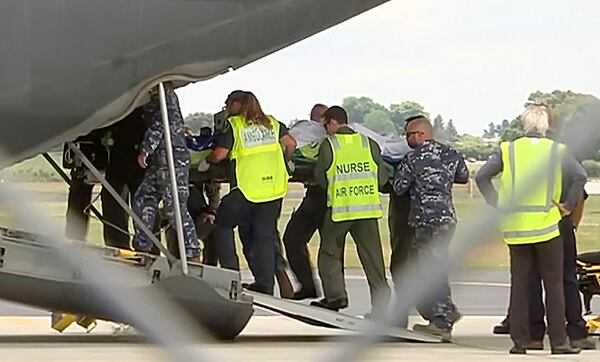 An injured tourist in the volcano eruption is carried Thursday to an Australian Air Force plane in Hamilton, New Zealand. New Zealand officials say they'll begin Friday to recover eight victims' bodies believed to remain on a small island since a volcanic explosion there earlier this week.