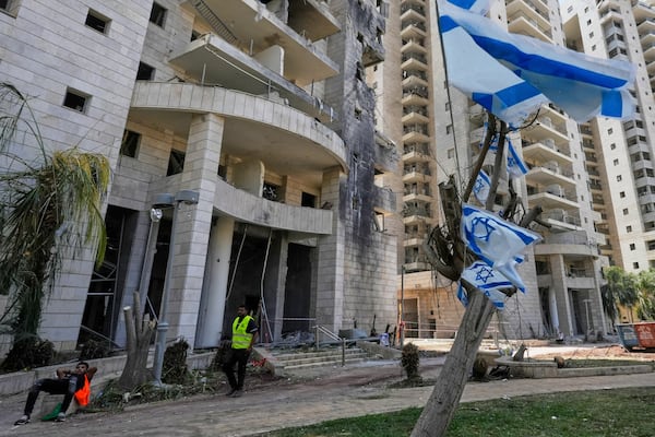 An Israeli security guard stands at the entrance of a residential building hit by a missile launched from Iran, in Petah Tikva, Israel, Monday, June 16, 2025. (AP Photo/Baz Ratner)