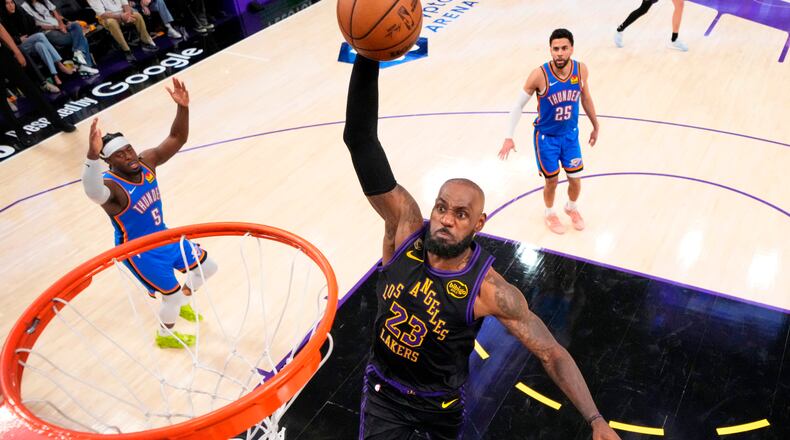 Los Angeles Lakers forward LeBron James, center, goes up for a dunk as Oklahoma City Thunder guard Luguentz Dort, left, and guard Ajay Mitchell watch during the second half of Game 4 in a second-round NBA basketball playoffs series Monday, May 11, 2026, in Los Angeles. (AP Photo/Mark J. Terrill)