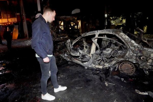 A man looks at a car destroyed in a Russian strike on Kharkiv, Ukraine, Saturday, March 29, 2025. (AP Photo/Andrii Marienko)