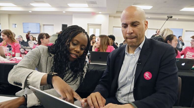 Cory Booker gets some assistance from Esosa Osa in Atlanta on Nov. 21 while texting people on his call list. Democratic presidential candidates including Cory Booker, Amy Klobuchar, Andrew Yang and Pete Buttigieg, along with Stacey Abrahms, were calling and texting voters whose registrations could be canceled in Georgia at a Fair Fight phone bank at Ebenezer Baptist Church. The phone bank was in response to Georgia election officials’ plan to cancel more than 313,000 voter registrations next month. Bob Andres / robert.andres@ajc.com