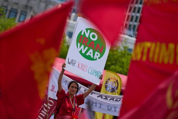 A woman holds a placard during a demonstration ahead of the NATO summit in The Hague, Netherlands, Sunday, June 22, 2025. (AP Photo/Peter Dejong)