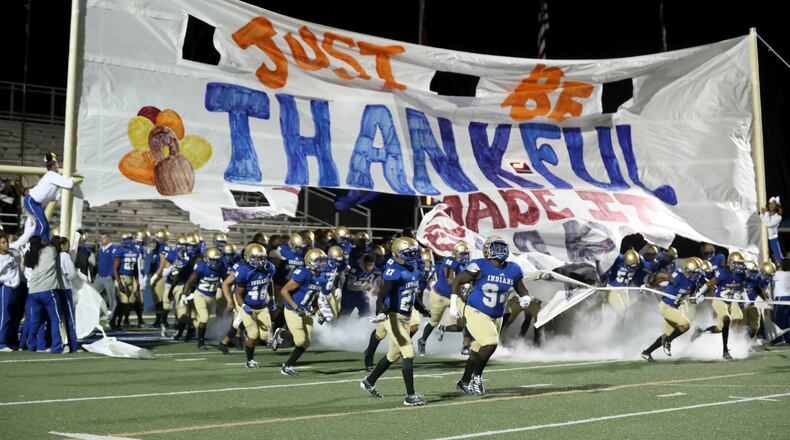 McEachern players run out of a banner that reads, "Just be thankful you made it this far," before their game against North Gwinnett in the Class 7A quarterfinals at McEachern High School Friday, Nov. 29, 2019, in Powder Springs.