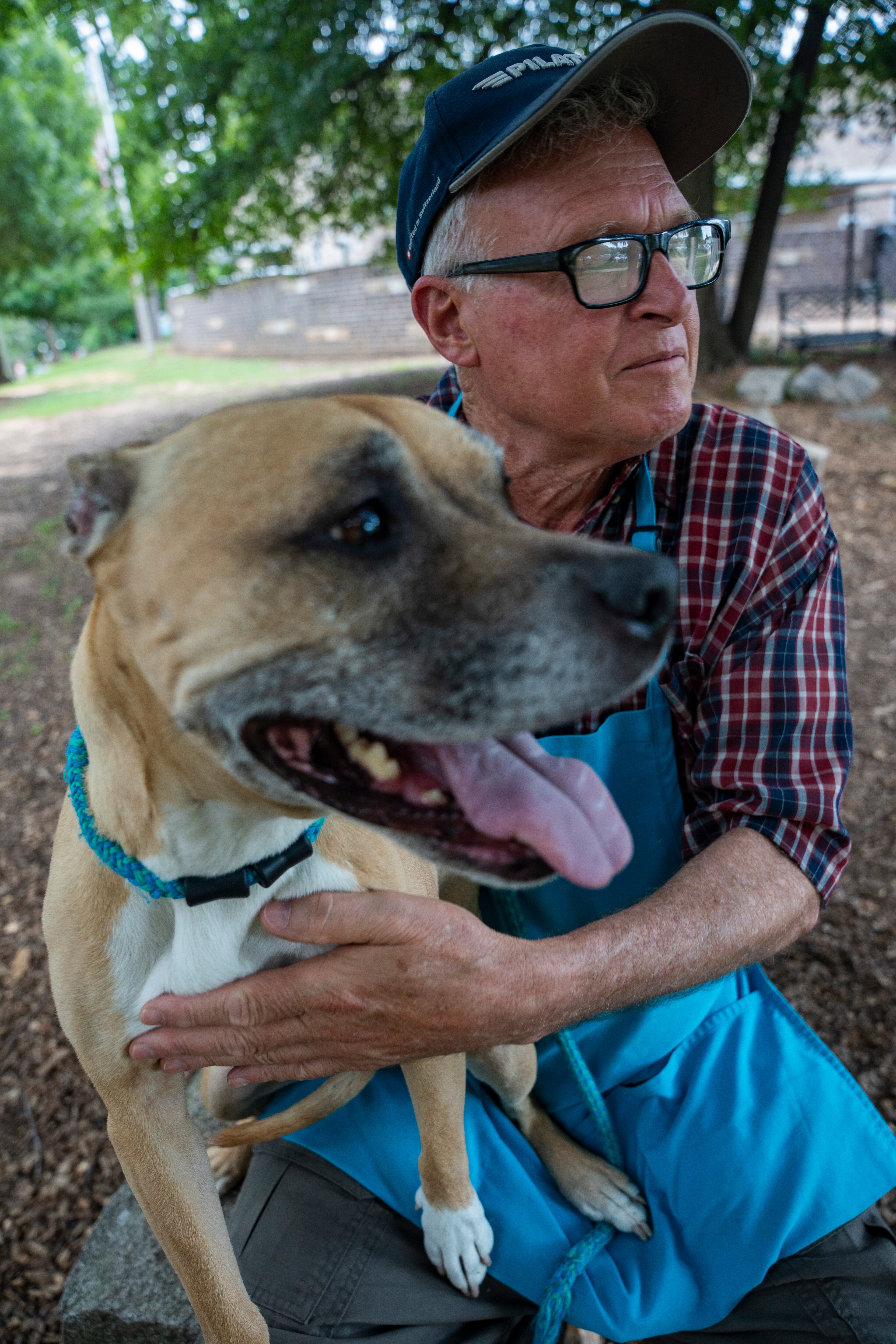Devoted volunteer Lee Gatewood sits with a dog, Cassandra, outside the DeKalb Animal Shelter on Tuesday, July 1, 2025, in Chamblee. (Olivia Bowdoin for the AJC)