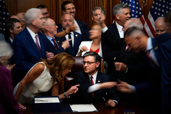 Republican members of Congress reach to shake hands with Speaker of the House Mike Johnson, R-La., center bottom, after Johnson signed President Donald Trump's signature bill of tax breaks and spending cuts, Thursday, July 3, 2025, at the Capitol in Washington. (AP Photo/Julia Demaree Nikhinson)
