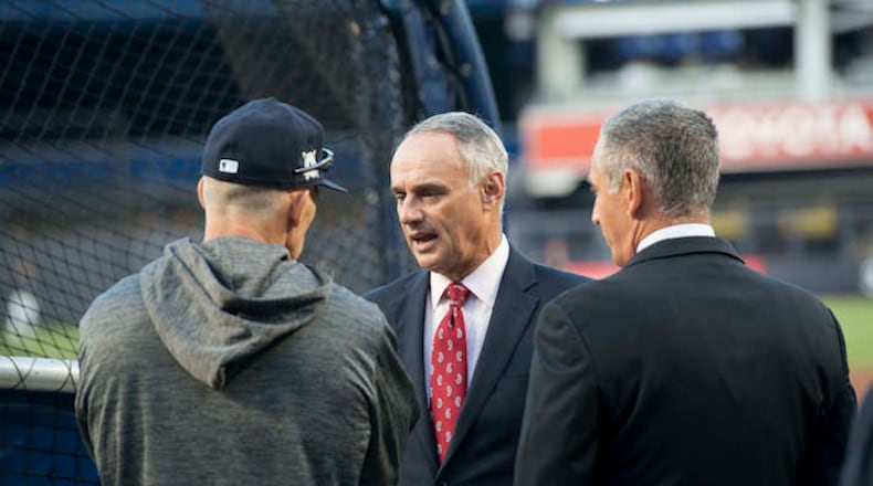 Major League Baseball Commissioner Rob Manfred talks with New York Yankees manager Joe Girardi before the American League Wild Card game against the Minnesota Twins at Yankee Stadium in New York on Tuesday, Oct. 3, 2017. (Howard Simmons/New York Daily News/TNS)