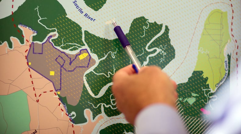 A Glynn County resident points to the mouth of the Satilla River near where the proposed spaceport will be located during a public hearing. The FAA recently released environmental impact study about the potential site, in brown to the left, for a spaceport in Kingsland, Georgia. The yellow marks indicate where rockets will be launched and land if approved by the FAA. (AJC Photo/Stephen B. Morton)