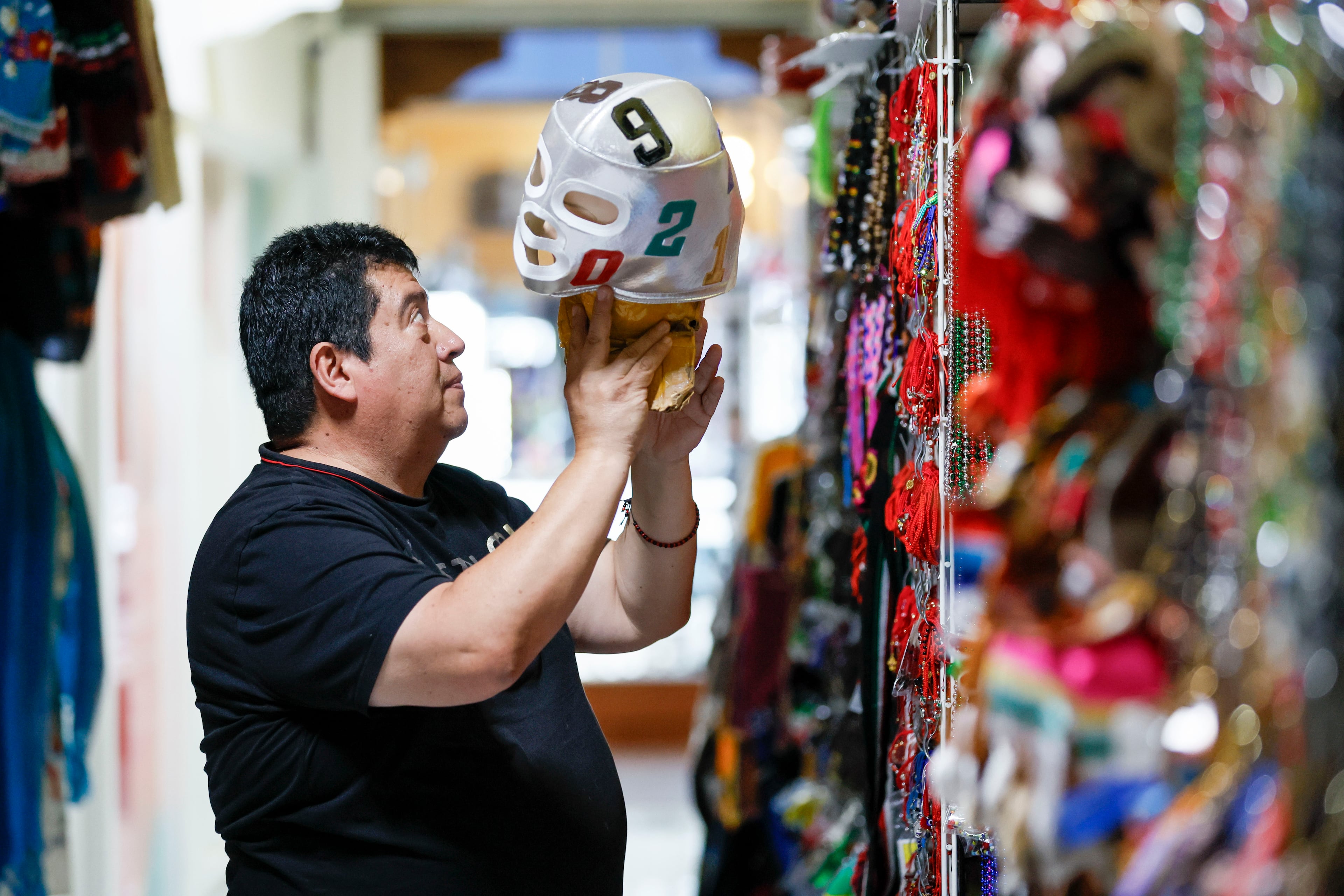 Jose Olague, owner of Olague’s Sports in Plaza Fiesta, works with merchandise at his store. Some shop owners have reported a decrease in business, which they attribute to the policies of the Trump administration. (Miguel Martinez/AJC)