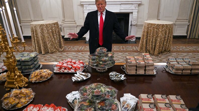 FILE - President Donald Trump talks to reporters about the table full of fast food in the State Dining Room of the White House in Washington, Jan. 14, 2019, for the reception for the Clemson Tigers. (AP Photo/Susan Walsh)