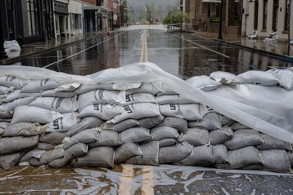 A flooded downtown area is seen past a stack of sandbags on Sunday, April 6, 2025, in Frankfort, Ky. (AP Photo/Jon Cherry)
