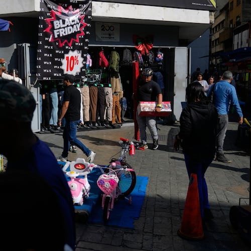 Pedestrians walk past a storefront promoting Black Friday discounts in Caracas, Venezuela, Friday, Nov. 28, 2025. (AP Photo/Ariana Cubillos)