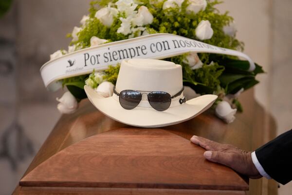 The hat and sunglasses of Dominican singer Rubby Perez, who died in the roof collapse at the Jet Set nightclub during his merengue concert, sit on his casket during his wake at the Eduardo Brito National Theater in Santo Domingo, Dominican Republic, Thursday, April 10, 2025. (AP Photo/Matias Delacroix)