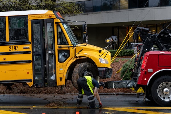 A Dekalb County School bus is loaded onto a tow truck along with a passenger car following an accident on Clairmont Road. Thursday, March 12, 2026 (Ben Hendren for the AJC)