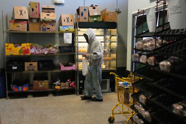 A man collects food staples at the Bishop Sullivan Center food pantry, Tuesday, April 15, 2025, in Kansas City, Mo. (AP Photo/Charlie Riedel)