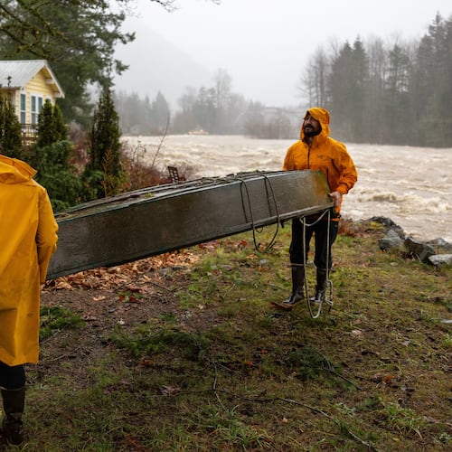Chad Walker, right, and Adrienne Higbee help an out-of-town neighbor with their property as the Skykomish River rises on Wednesday, Dec. 10, 2025, in Index, Snohomish County, Wash. (Nick Wagner /The Seattle Times via AP)
