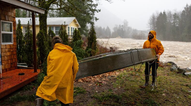 Chad Walker, right, and Adrienne Higbee help an out-of-town neighbor with their property as the Skykomish River rises on Wednesday, Dec. 10, 2025, in Index, Snohomish County, Wash. (Nick Wagner /The Seattle Times via AP)