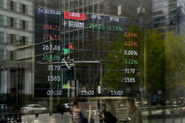 Pedestrian are reflected on a brokerage house's window as an electronic board displays shares trading index, in Beijing, Monday, April 7, 2025. (AP Photo/Andy Wong)