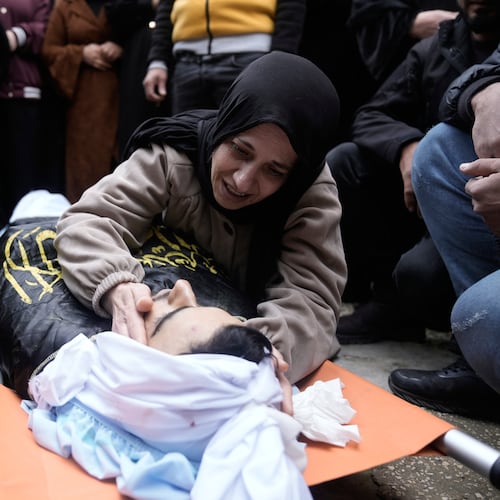 Palestinian mother of Ahmad Ziyoud, draped in the flag of the Islamic Jihad militant group, mourns during his funeral in Silat al-Harithiya, near Jenin, in the West Bank, Sunday, Dec. 21, 2025. (AP Photo/Majdi Mohammad)
