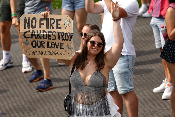 A woman holds a placard as Odymel B2B and Pegassi perform at the Tomorrowland music festival in Boom, Belgium, Friday, July 18, 2025, two days after a huge fire on Wednesday severely damaged the main stage. (AP Photo/Omar Havana)